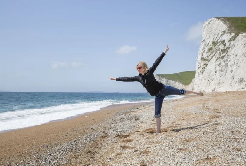 Frau balanciert auf einem Bein am Strand