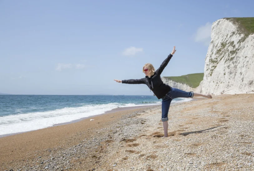 Frau balanciert auf einem Bein am Strand